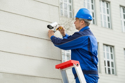 Mature Technician Installing Camera On Wall With Screwdriver