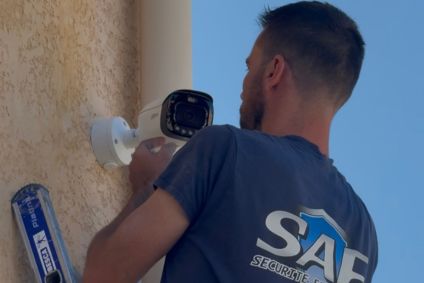 Mature Technician Installing Camera On Wall With Screwdriver